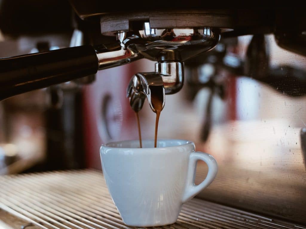 Taza de café en una cafetera como muestra de loslbeneficios del café.