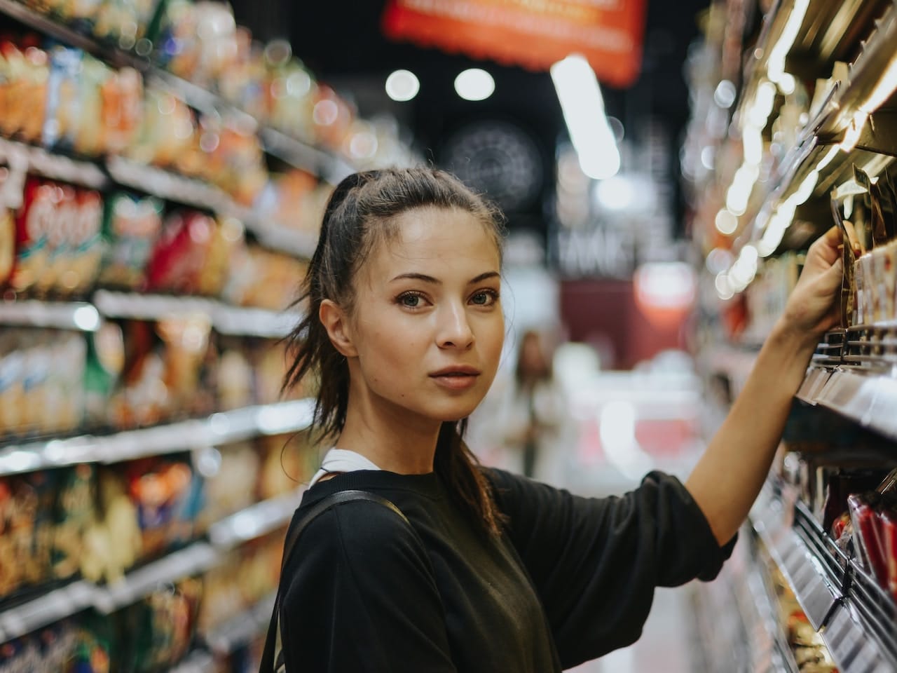 Chica en un supermercado lee eqtiquetados para localizar los alérgenos de declaración obligatoria