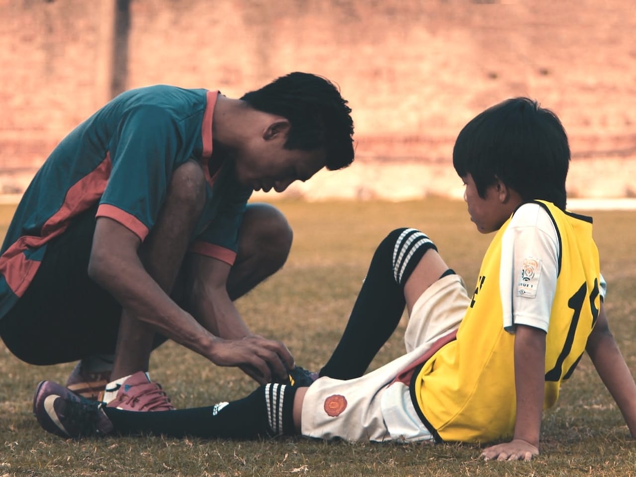 Entrenador ayuda a un niño lesionado y sugiere alimentación para recuperación muscular