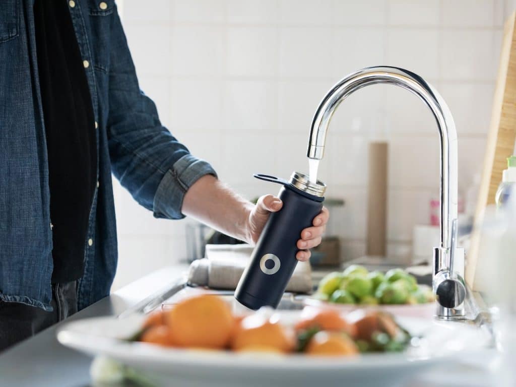 Hombre llena un bidón de agua en la cocina para evitar la hjinchazón abdominal