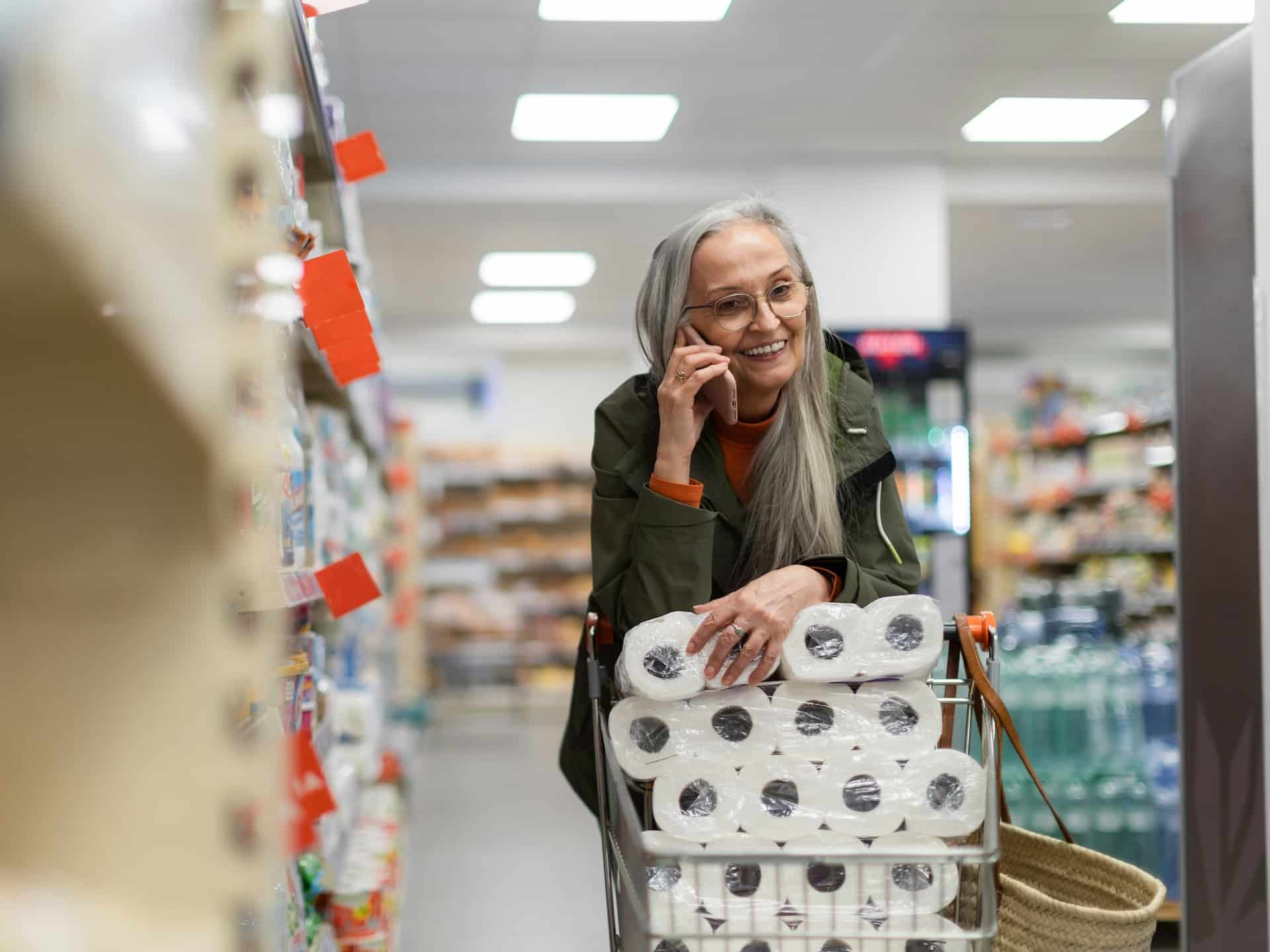 Mujer con un carrito de la compra lleva rollos de papel higiénico