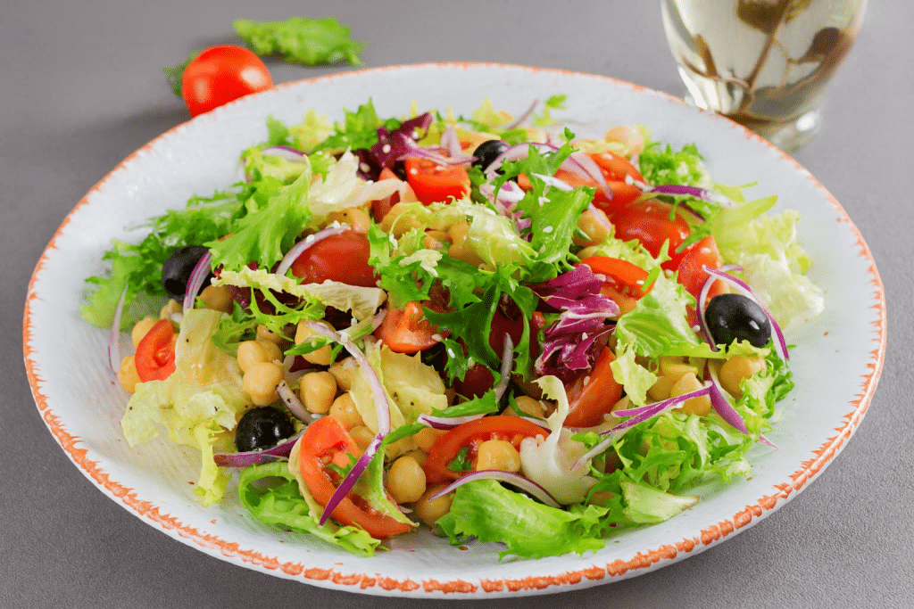 Ensalada con garbanzos y verduras en un plato blanco, opci&oacute;n saludable y f&aacute;cil de preparar