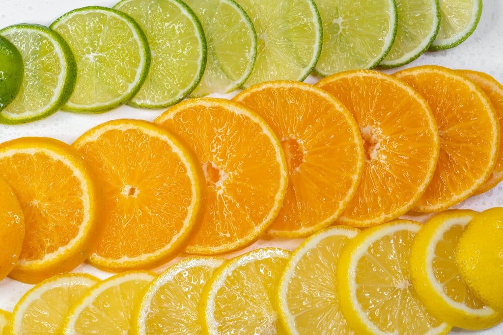 : Rodajas frescas de limones, limas y naranjas dispuestas en degradado de color.